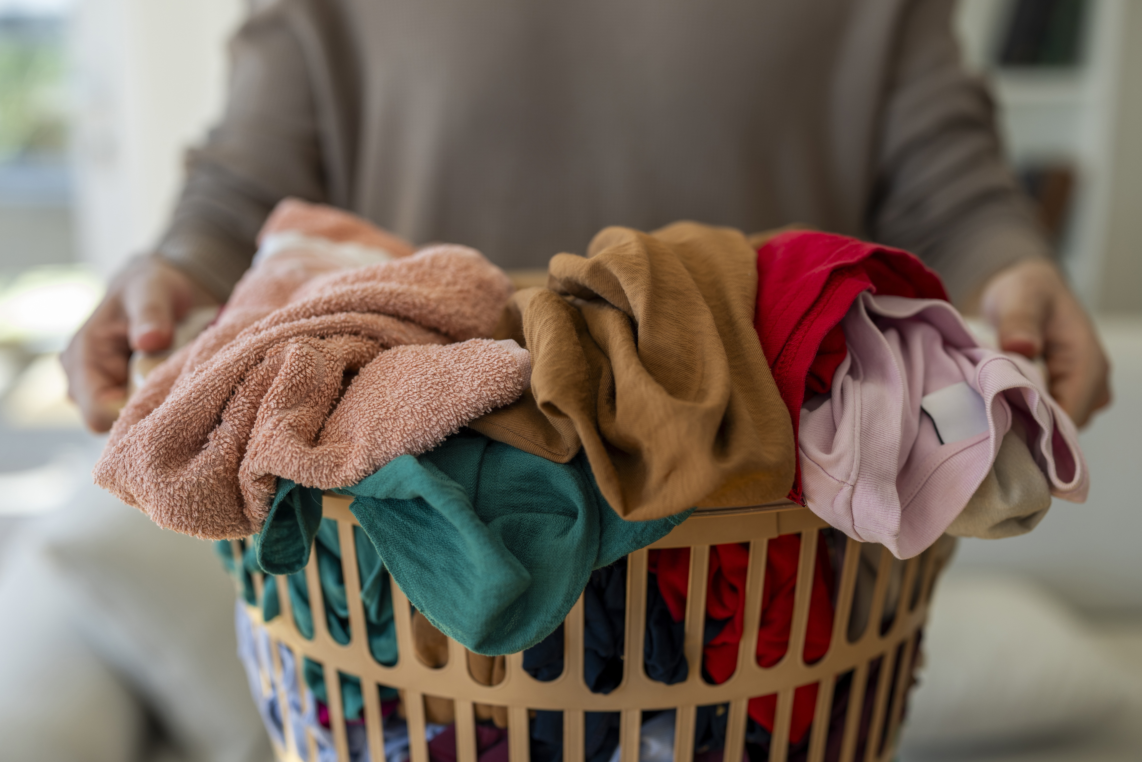 A person holding a full laundry basket of clothes